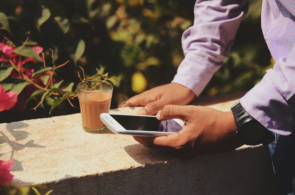 man med telefon och kaffekopp